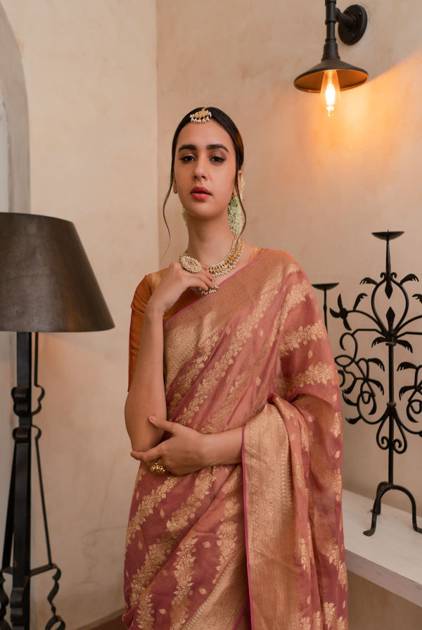 A woman wearing pure georgette tissue saree in dusty rose, latest saree, new saree collection