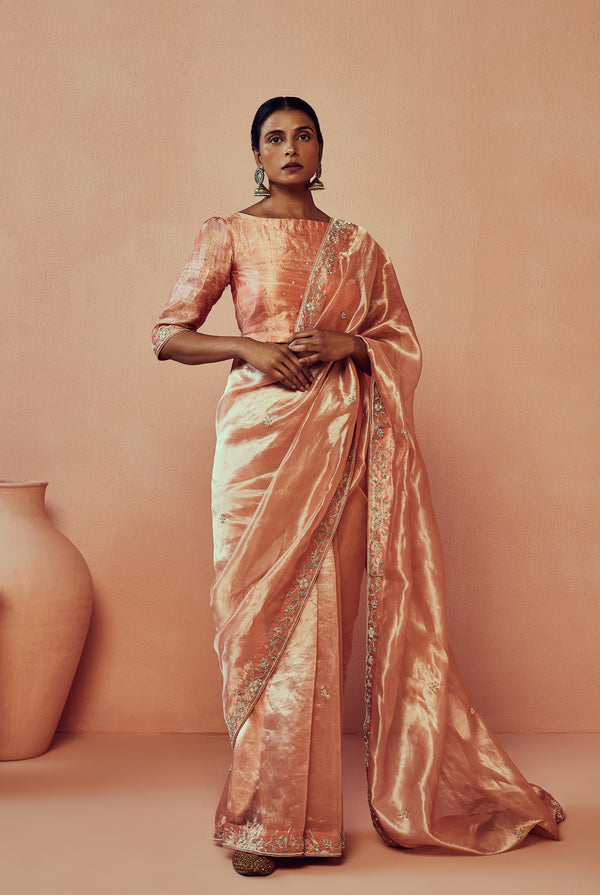 A women wearing peach pure tissue saree with handwork, traditional wear for women.