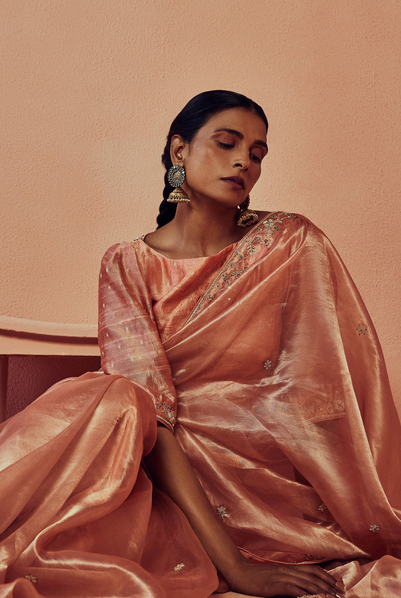 A women wearing peach pure tissue saree with handwork, traditional wear for women.