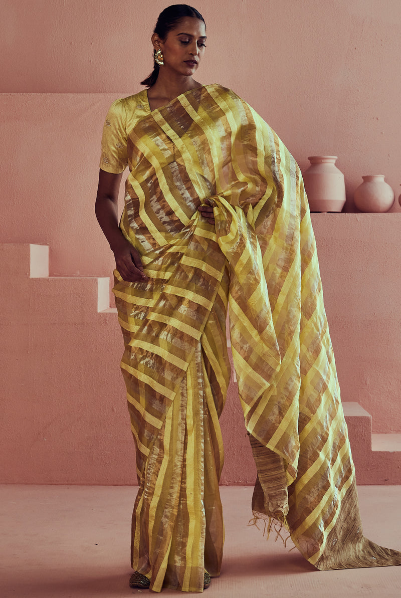 A women wearing yellow pure tissue striped saree, party wear for women.